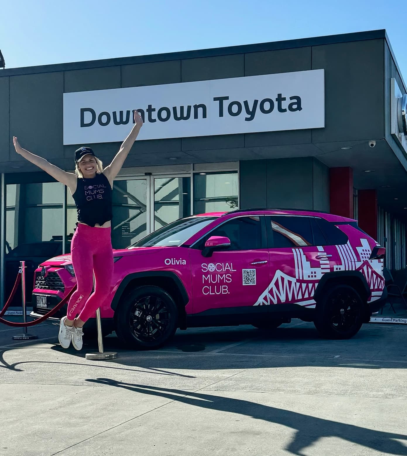 Kirsty Foster jumping outside Downtown Toyota with Olivia the pink RAV4